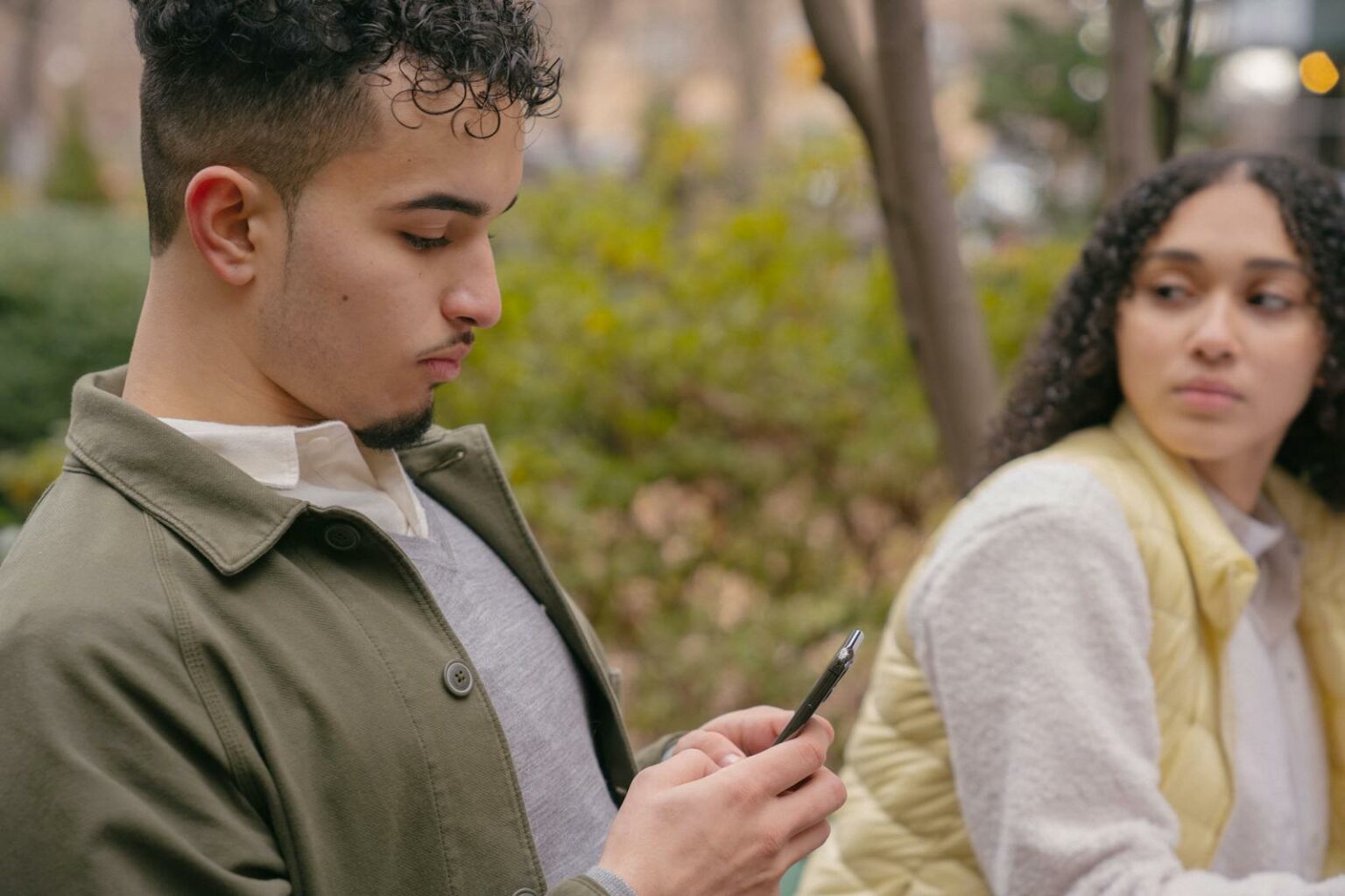 Hispanic lady looking jealously at boyfriend while texting on cellphone