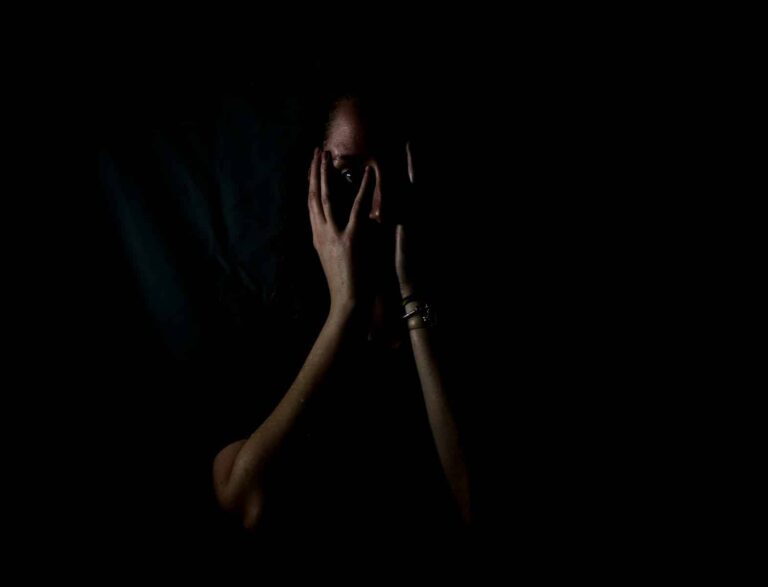 woman holding her face in dark room