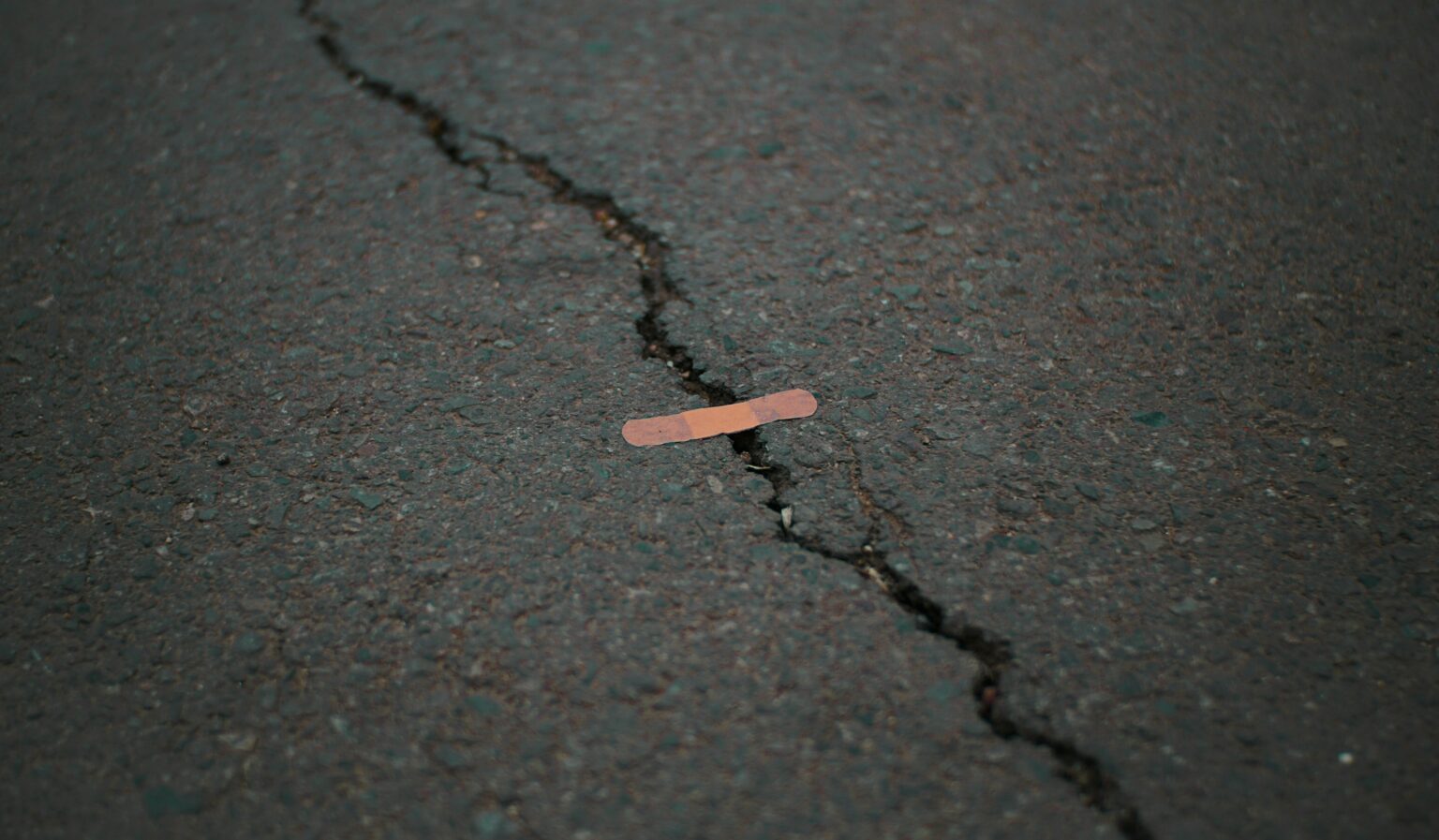 orange band aid on concrete surface crack