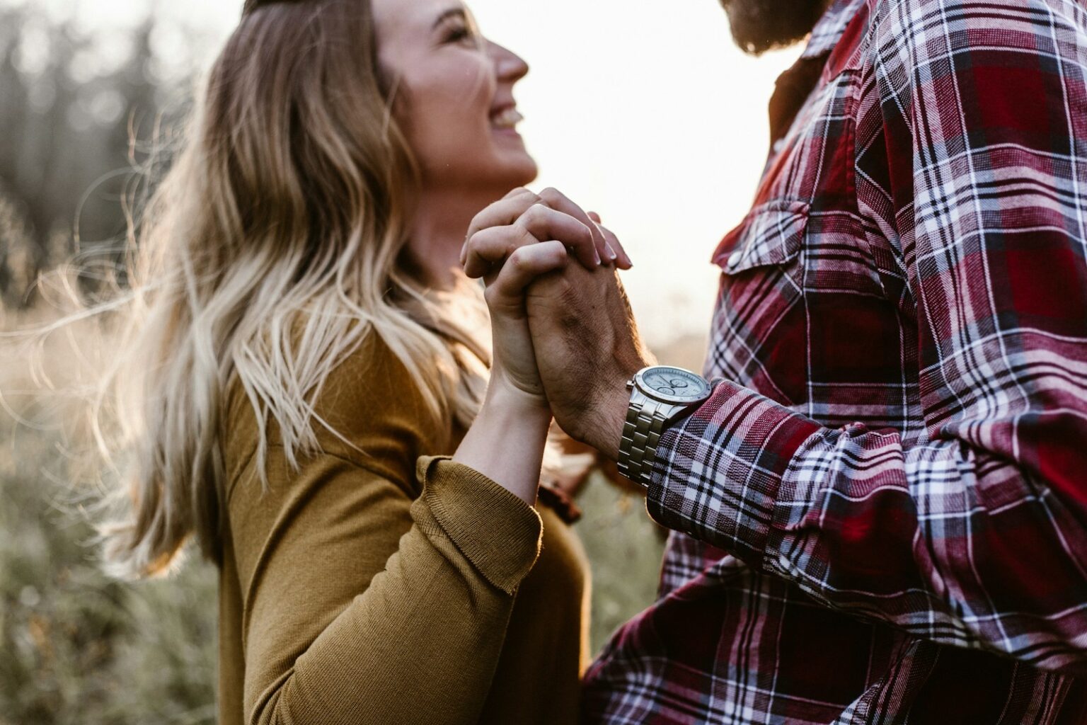 woman in front of man holding each hands each other near green trees