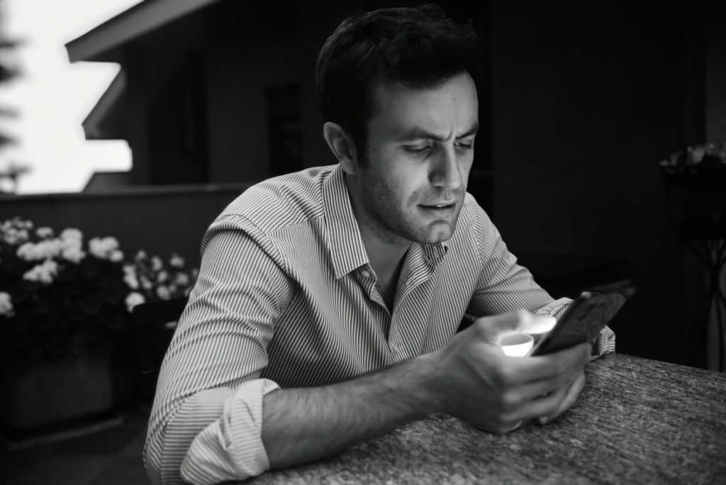 a man sitting at a table looking at a cell phone