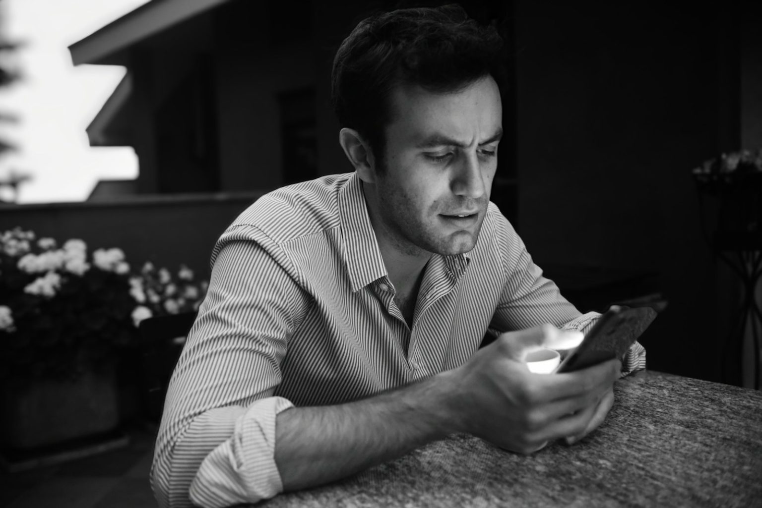 a man sitting at a table looking at a cell phone